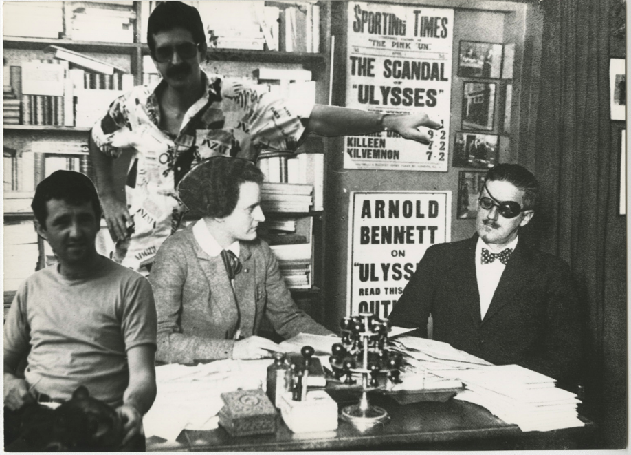 Foto en blanco y negro de un grupo de personas alrededor de una mesa

Descripción generada automáticamente